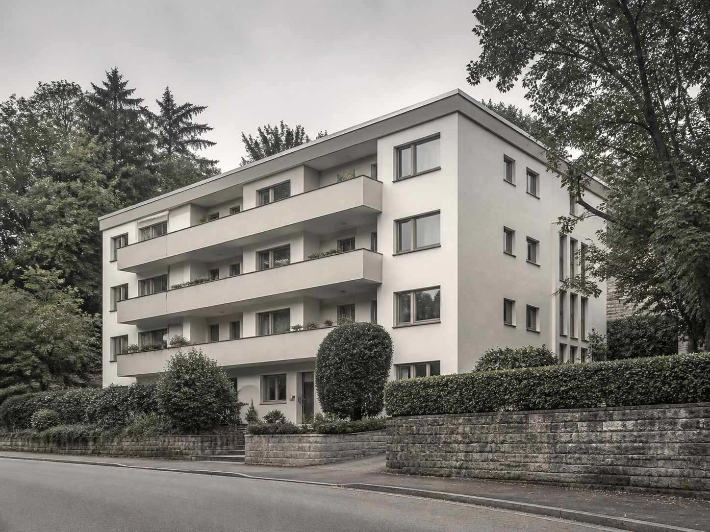 Modernes Wohngebäude an einem begrünten Hang oberhalb einer Straße
